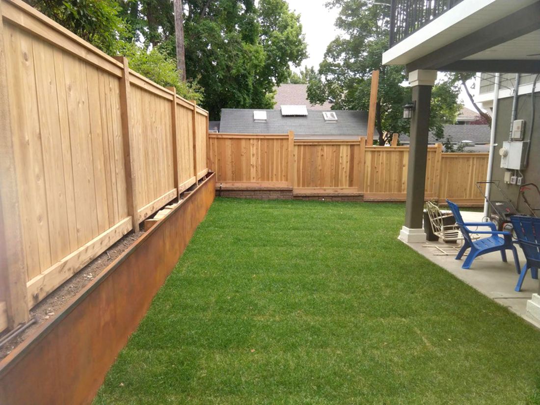 Cedar privacy fence enclosing a green backyard with a covered patio