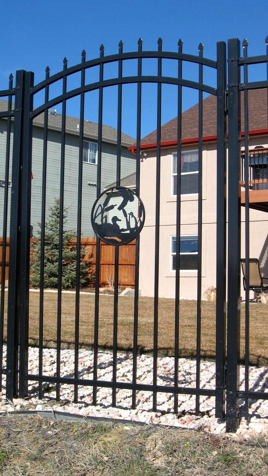 An arched ornamental iron gate with a custom duck medallion