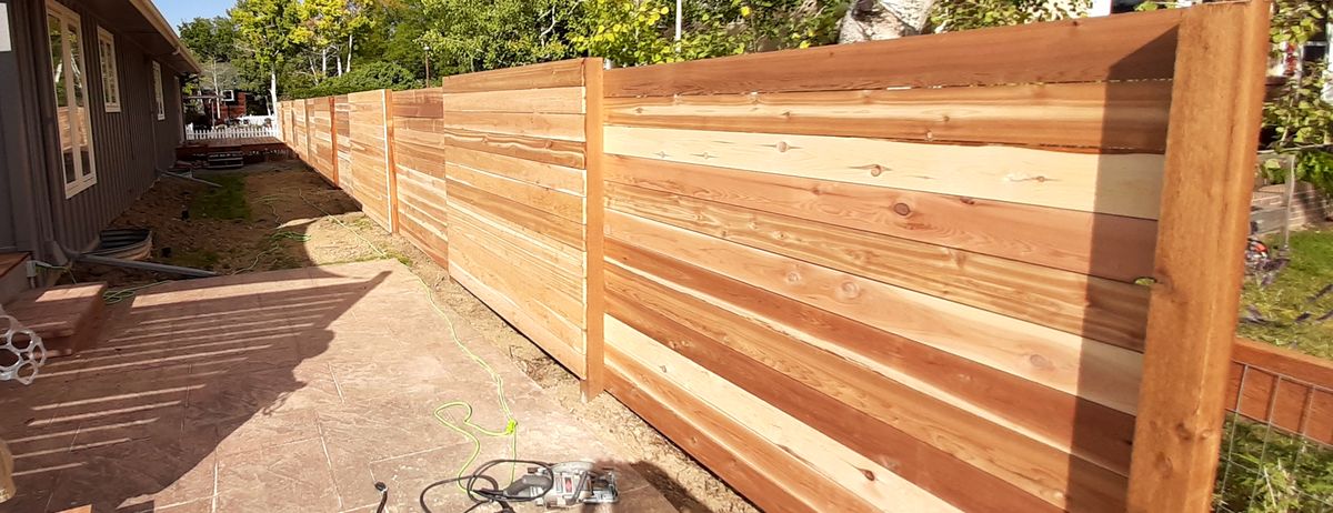 A new horizontal cedar privacy fence installed along a backyard patio